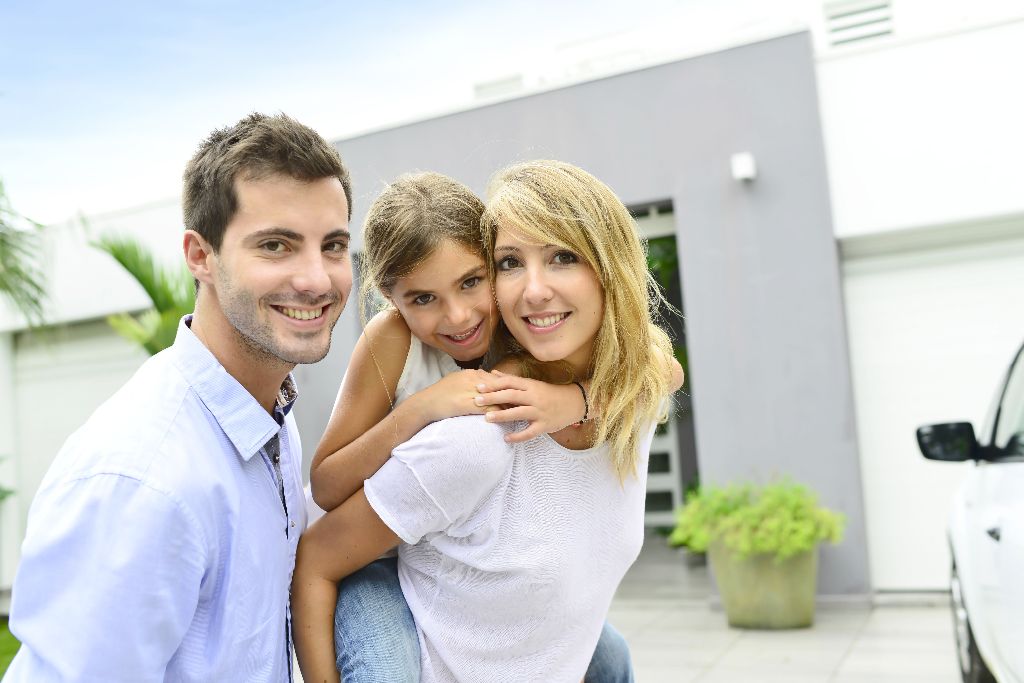 Parents with kid standing in front of new home